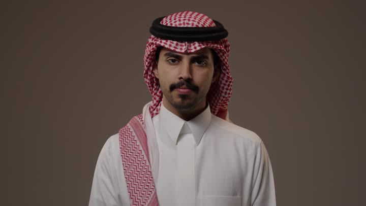 رفع اصبع الابهام للاسفل مع ضم باقى الاصابع اشارة الى عدم الاعجاب بشئ ما , رجل عربي خليجي سعودي يرتدي الزي  التقليدي الابيض في المملكة العربية السعودية , تعابير وجه غضبان غير راضي