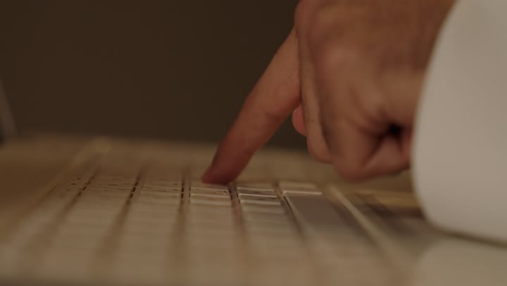 A Saudi Arabian Gulf Arab man wearing a white thobe is sending work-related emails, clicking on the keyboard professionally, quickly sending messages and easily reaching anywhere.