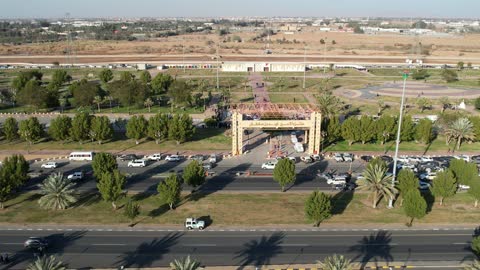 The focus on planting green plants and trees in the city, drone footage of a car parade on one of the streets in the Kingdom of Saudi Arabia during the daytime.