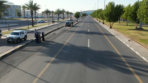 الاهتمام بزراعة النبات الاخضر والشجر في المدينة، تصوير درون لمسيرة سيارات في إحدى شوارع المملكة العربية السعودية في وقت النهار