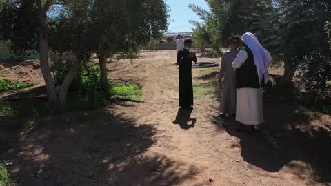 رجل عربي يرتدي اللباس التقليدي، مسار للمشي بين أشجار النخيل والحمضيات، من المزرعة إلى المائدة، تصوير درون لمزارع العلا في المملكة العربية السعودية،  أكبر المزارع التي توفر خيارات للإقامة الريفية