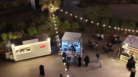 مكان لقضاء وقت ممتع مع العائلة في المملكة العربية السعودية، الفن الهندسي المعماري على الطراز الحديث، وجهة تسوق وترفيه عائلية ، تصوير درون للبارك مول في وقت الليل على طريق الملك فيصل في حي مروج الأمير في مدينة تبوك