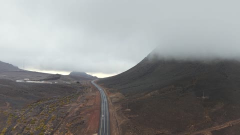 تساقط البرد (حبات الثلج الصغيرة) فوق منطقة الحرات البركانية في تبوك، الجو الشتوي الضبابي فوق الجبل في سماء مدينة حرة تبوك في المملكة العربية السعودية