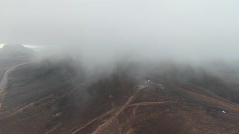 الجو الشتوي الضبابي فوق الجبل في سماء مدينة حرة تبوك في المملكة العربية السعودية، تساقط البرد (حبات الثلج الصغيرة) فوق منطقة الحرات البركانية في تبوك