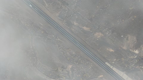 الجو الشتوي الضبابي فوق الجبل في سماء مدينة حرة تبوك في المملكة العربية السعودية، تساقط البرد (حبات الثلج الصغيرة) فوق منطقة الحرات البركانية في تبوك