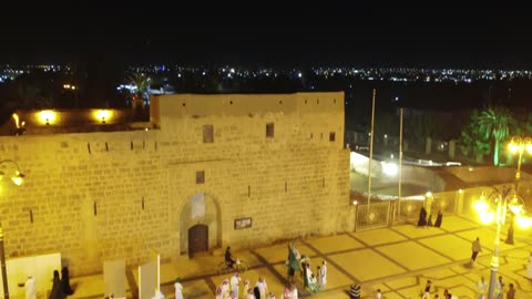 A group wearing traditional attire, the thobe and shemagh, the Tabuk Castle is a historical landmark located in the center of Tabuk city in the Kingdom of Saudi Arabia. It has a courtyard overlooking several rooms, a mosque, and a well. The castle has recently been restored and is now a historical, cultural, and tourist destination.