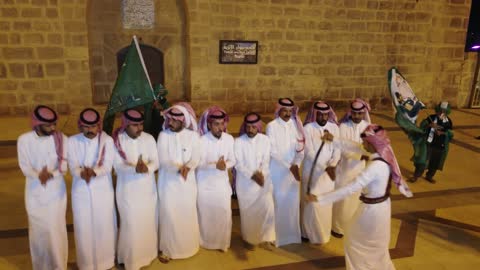 A courtyard overlooking several rooms, a mosque, and a well, with men wearing traditional attire of thobe and ghutrah. Tabuk Castle is a historical landmark located in the center of Tabuk city in the Kingdom of Saudi Arabia. The castle has recently been restored and is now a historical, cultural, and tourist destination.