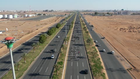 الاهتمام بزراعة النبات الاخضر والشجر في المدينة، تصوير درون لمسيرة سيارات في إحدى شوارع المملكة العربية السعودية في وقت النهار