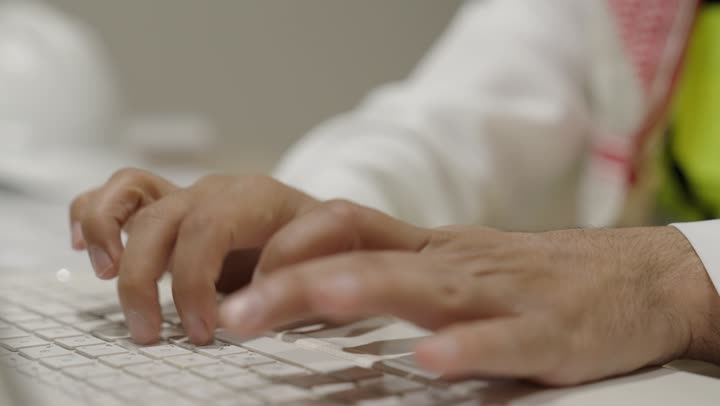 النقر على لوحة المفاتيح، صناعة المحتويات النصية، مفهوم ادخال البيانات، تصوير مقرب ليد مهندس عربي خليجي سعودي يرتدي سترة الحماية يقوم بالعمل على الحاسوب المحمول، الكتابة على جهازاللابتوب، دمج التكنولوجيا الحديثة بالحياة العملية، متابعة مخطط المشروع الهندسي اونلاين