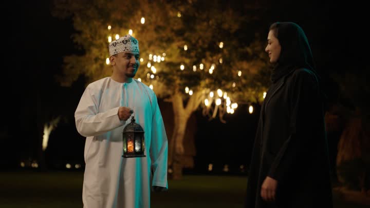 استقبال شهر الخير والبركة، المناسبة الدينية والعيد الإسلامي، الاستعداد لقدوم شهر رمضان, رجل عربي خليجي عماني يرتدي الدشداشة و الكمة يقوم باعطاء زوجته فانوس معدني, تحف وزينة الاحتفالات في سلطنه عمان، تعابير السعادة و السرور