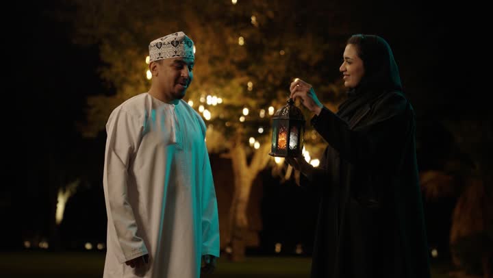 المناسبة الدينية والعيد الإسلامي، استقبال شهر الخير والبركة، الاستعداد لقدوم شهر رمضان, رجل عربي خليجي عماني يرتدي الدشداشة و الكمة يقوم باعطاء زوجته فانوس معدني, تحف وزينة الاحتفالات في سلطنه عمان، تعابير السعادة و السرور