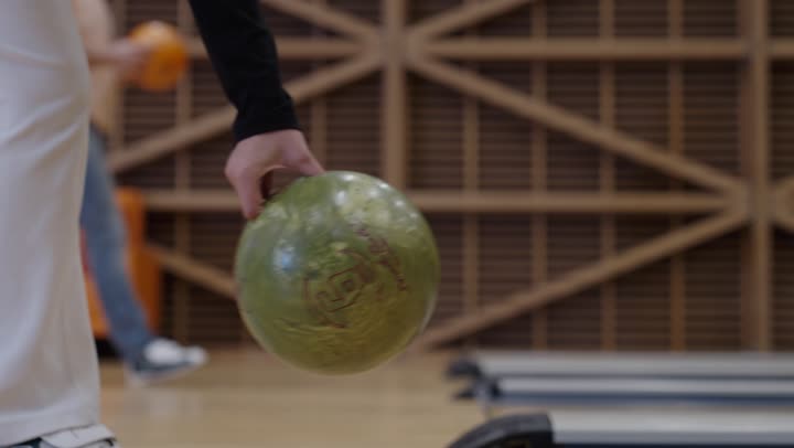 الاستعداد لبداية مباراة البولينغ , رمي الكرات المعدنية من نقطة الانطلاق ,فتاة وشاب عربيان خليجيان سعوديان يحملون الكرة استعدادًا لرميها ,التصفيق و الفرحة بعد تحقيق الفوز , نشاط ترفيهي عائلي في صالة البولينج