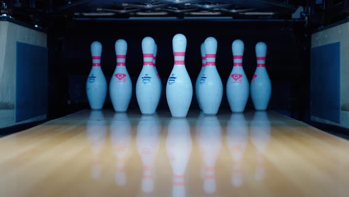 سقوط دبابيس رياضة البولينغ البلاستيكية عند اصطدام الكرة بها ,ارتطام الكرة المعدنية مسببة سقوط الزجاجات الملونة لتسجيل النتيجة , نشاط ترفيهي عائلي , نشاط ترفيهي عائلي في صالة البولينج