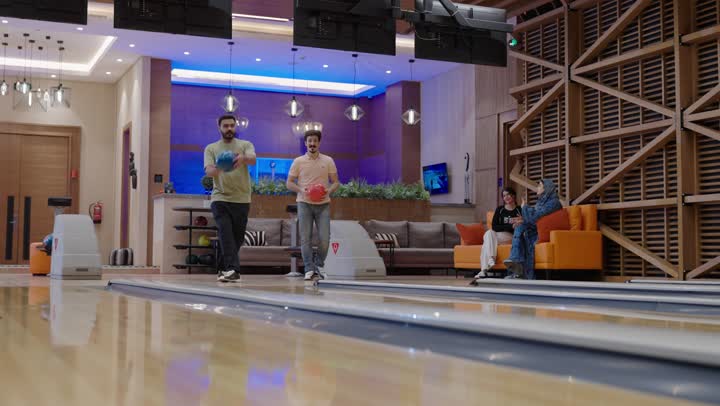 التنافس بين الاصدقاء في لعبة البولينج ,الدقة والاحتراف في رمي الكرة,اجتماع العائلة للتسلية والترفيه في صالة البولينغ ,نشاط ترفيهي عائلي