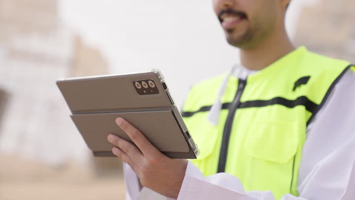 الإشراف على محطات توليد الكهرباء, استخدام التقنية والتكنولوجيا في المشاريع المستقبلية,  مهندس طاقة عربي خليجي عمانى يحمل بيده جهاز تقني، إرتداء خوذة وسترة الحماية الخاصة بالعمل