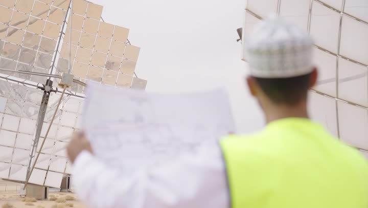 تدقيق ومراجعة الخطط الهندسية، دراسة أساسيات المشروع, تصوير من الخلف لمهندس عربي خليجي عماني يرتدي الدشداشة والكمة و سترة الحماية,  مهن ووظائف للشباب في سلطنة عمان