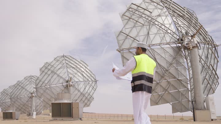 Project management with professionalism, an Arab Gulf Omani engineer wearing a dishdasha, a kumma, and a safety vest looks with gestures of joy while holding engineering plans and designs, professions and jobs for youth in the Sultanate of Oman.