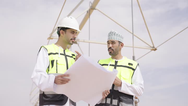 دراسة أساسيات المشروع الهندسى, مهندسان عربيان خليجيان عمانيان يشرفان على محطات الطاقة الشمسية ، إرتداء خوذة وسترة الحماية ، الإشراف على العمل، ستلايت، أنظمة الطاقة الشمسية,  تبادل الخبرة و الرأى,