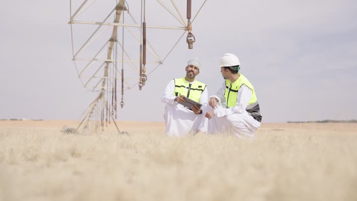 مهندسان عربيان خليجيان عمانيان يشرفان على محطات الطاقة الشمسية ، إرتداء خوذة وسترة الحماية ، الإشراف على العمل، ستلايت، أنظمة الطاقة الشمسية، تبادل الخبرة و الرأى