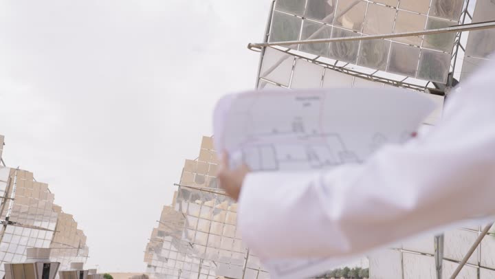 دراسة ومراجعة المخططات الهندسية, تصوير مقرب ليد مهندس عربي خليجي عمانى يقف في مقر العمل و يحمل مخطط هندسى,  مفهوم هندسة الطاقة، مهن ووظائف عمانية، محطات الطاقة الشمسية