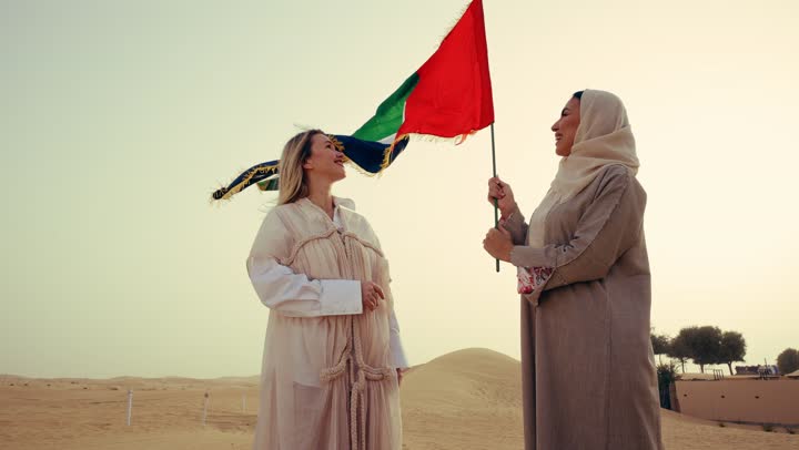 يوم الاتحاد 2 ديسمبر، امراتان عربيتان خليجيتان اماراتيان يرتديان العباءة يقفان فى الصحراء يمسكان علم الامارات العربية المتحدة، ذكرى يوم العلم 3 نوفمبر, إحياء ذكرى اليوم الوطني الاماراتي 1971, مفهوم حب الوطن والانتماء إليه