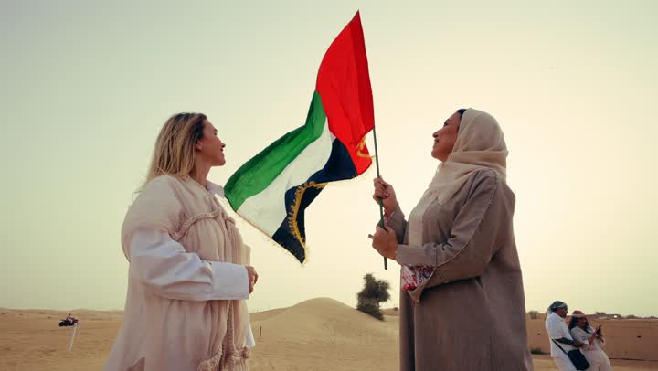 مفهوم حب الوطن والانتماء إليه، يوم الاتحاد 2 ديسمبر، امراتان عربيتان خليجيتان اماراتيان يرتديان العباءة يقفان فى الصحراء يمسكان علم الامارات العربية المتحدة، ذكرى يوم العلم 3 نوفمبر, إحياء ذكرى اليوم الوطني الاماراتي 1971