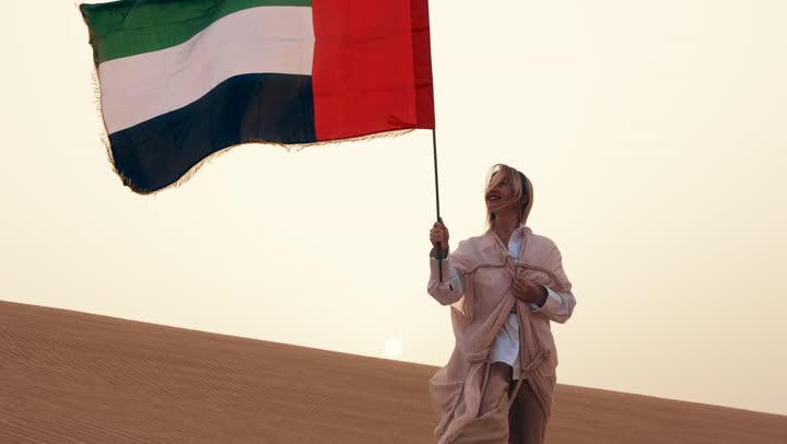 Love of the homeland and belonging to it, celebrating the anniversary of the independence of the United Arab Emirates, an Arab Gulf Emirati woman wearing an abaya standing in the desert, gestures of happiness, pride, and honor, the concept of love for the homeland and belonging to it.