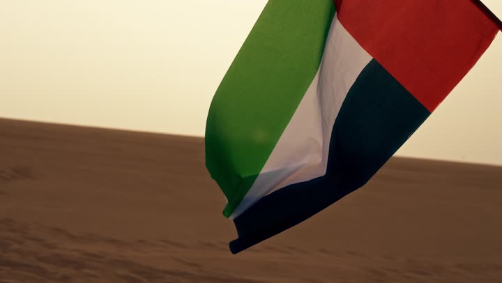 The UAE National Day is on December 2nd, the flag of the United Arab Emirates flutters amidst the desert areas, the soft golden sands, the concept of love for the homeland and belonging to it, the formations and structures of sand in the desert.