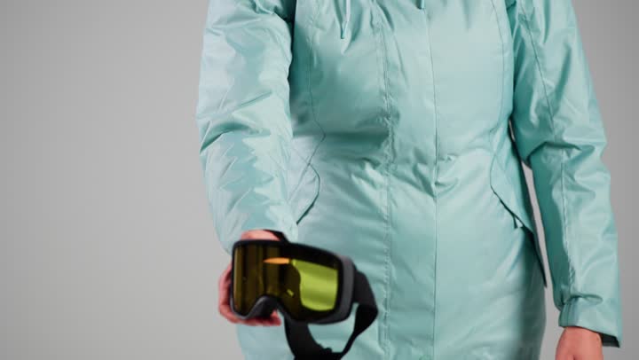 تصوير مقرب لنظارة جليد صفراء , امرأة عربية خليجية سعودية ترتدي المعطف الازرق الثقيل , حماية العيون من تطاير الثلج الصغير , امراة اماراتية