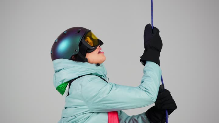 الوصول بالعلم الاماراتي للقمة , امراة اماراتية ترتدي ملابس التزلج على الجليد الثقيلة تشد الحبل بصعوبة , ممارسة الانشطة الممتعة في الاجواء الشتوية الباردة