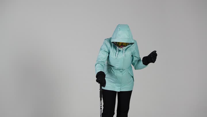 المشي على الجليد بصعوبة , امرأة عربية خليجية سعودية ترتدي ملابس التزلج على الجليد , الاستناد على العصا لسهولة الحركة و التوازن , امرأة اماراتية , انشطة شتوية باردة