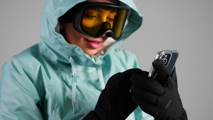 لمس شاشة الهاتف بسهولة مع ارتداء القفازات الثقيلة , امرأة عربية خليجية سعودية ترتدي ملابس التزلج على الجليد , امرأة اماراتية , تعابير الدهشة و الذهول