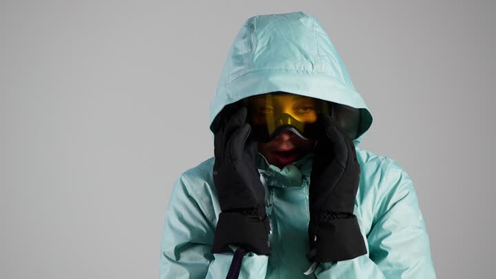 الاحتضان و فرك اليدين بالجسم للشعور بالدفء , امرأة عربية خليجية سعودية ترتدي ملابس التزلج على الجليد الثقيلة للتغلب على موجة الصقيع , تعابير الاحساس بالبرودة , نفث الزفير في الكفين , امرأة اماراتية