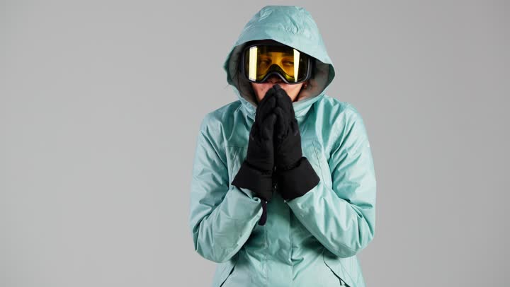 الزفير في الكفيين للشعور بالدفء , امرأة عربية خليجية سعودية ترتدي ملابس التزلج على الجليد , الاحساس بالبرد و الصقيع , النظر للكاميرا , امراة اماراتية ,ارتداء الملابس الثقيلة