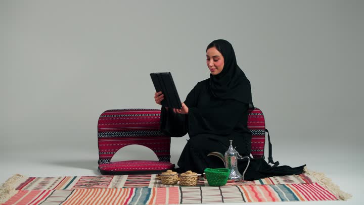 الترحيب والسلام بكف اليد , امرأة عربية خليجية سعودية محجبة ترتدي العباءة السوداء تحمل كوب صغير من القهوة , اجراء مكالمات الفيديو المباشرة من اي مكان بسهولة مع التغطية القوية للاتصال , ايماءات السعادة و الفرحة , امرأة اماراتية