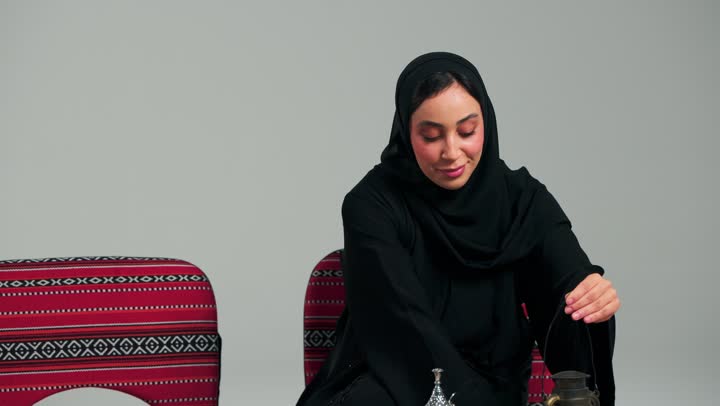 امرأة عربية خليجية سعودية محجبة ترتدي العباءة السوداء تشعل المصباح احتفالاً بشهر رمضان , الجلوس على المفرش و الاستمتاع بالاجواء الشتوية , امرأة اماراتية