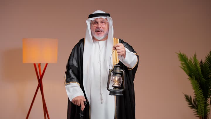 مرحب مرحب يا هلال , رجل عربي خليجي سعودي مسن يرتدي الثوب الابيض التقليدي في المملكة العربية السعودية يحمل الفانوس احتفالاً بالشهر الفضيل , ايماءات السعادة و البهجة , الغترة البيضاء الناصعة و مشلح اسود انيق
