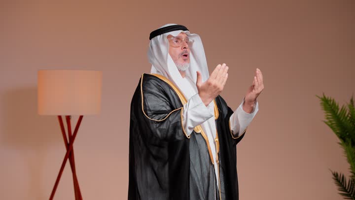 الوقوف امام الكاميرا وسؤال الله الصحة و سعة الارزاق , رجل عربي خليجي سعودي مسن يرفع اليدين للدعاء و التقرب الى الله