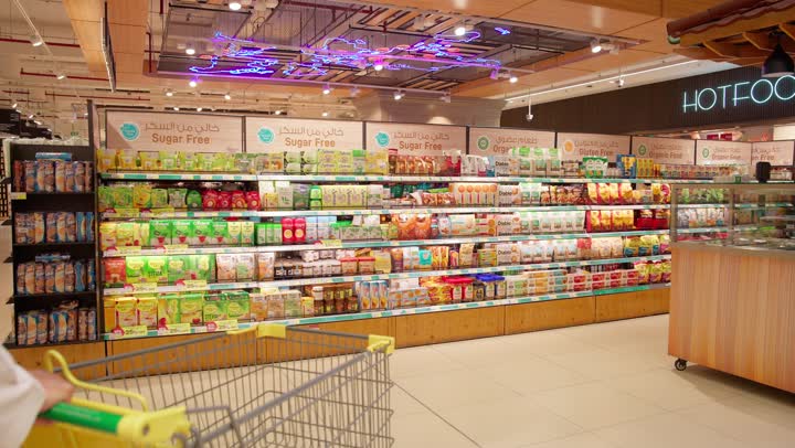 الاستفادة من الخصومات والعروض، المشاركة في شراء المستلزمات المنزلية، زوجان عربيان خليجيان اماراتيان يرتديان الزي التقليدي يقومان بجرعربة التسوق برفقة ابنتهم، شراء المنتجات من السوبر ماركت، التجول في المول والمركز التجاري