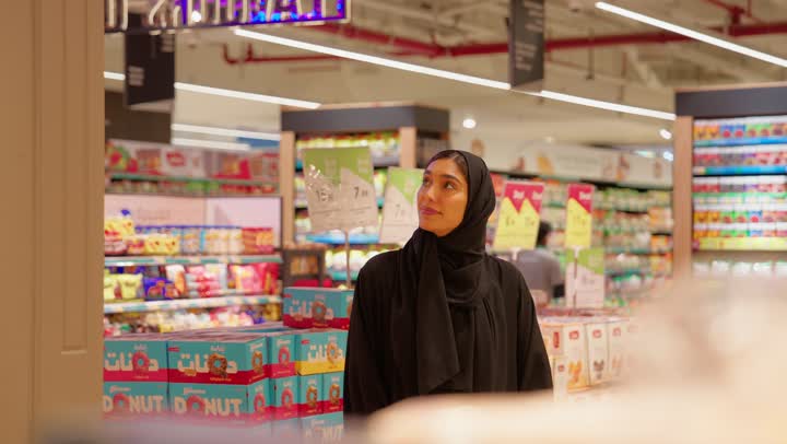 الاستفادة من العروض والتخفيضات، مفهوم التسوق وشراء المخبوزات والمعجنات، تصوير مقرب لامرأة عربية خليجيه اماراتية ترتدي العباءة والحجاب تقوم بالتسوق داخل السوبر ماركت، التسوق اليومي داخل المتجر