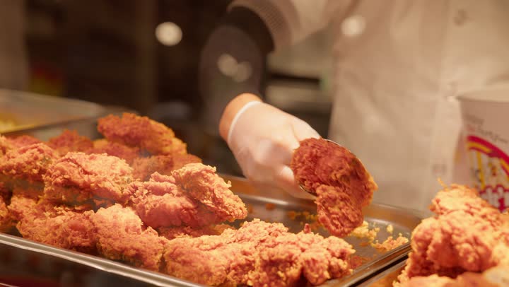 وجبات سريعة جاهزة للأكل داخل قسم الديلي، تصوير مقرب ليد عامل عربي خليجي اماراتي داخل قسم الأطعمة الجاهزة في السوبر ماركت  يقوم بتقديم قطع الدجاج المقلي باستخدام ملقط معدني، مفهوم شراء الطعام الجاهز، دجاج مقرمش طازج، خدمة العملاء داخل المتجر