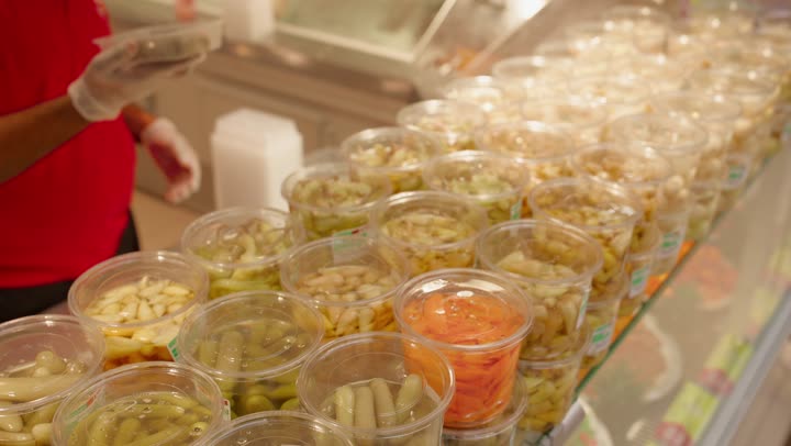 اختيار المنتجات الغذائية الجاهزة عالية الجودة، تصوير مقرب لرجل عربي خليجي اماراتي يرتدي الكندورة يقوم بشراء المخللات الجاهزة من قسم الأطعمة المحفوظة داخل السوبر ماركت، مفهوم التسوق اليومي