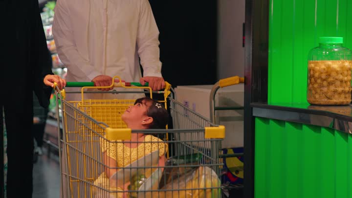 An Emirati Gulf Arab girl inside the supermarket pointing to fresh juice products, family shopping and buying cold drinks, the concept of caring about healthy nutrition for children, gestures of happiness and joy, spending quality time with the family while shopping.