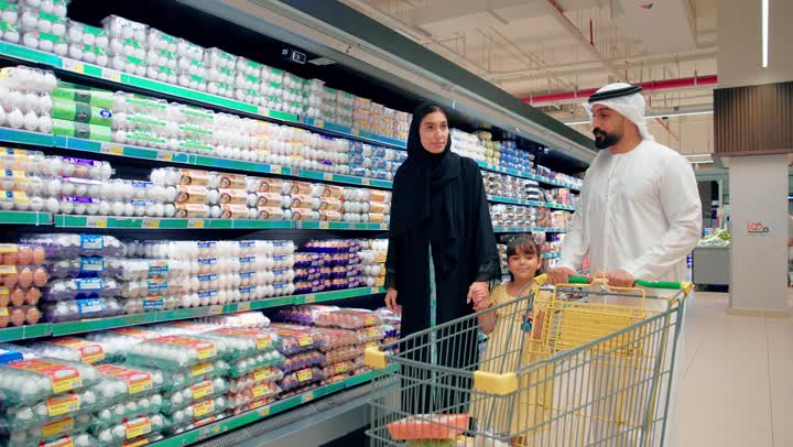 اختيار وشراء المنتجات الغذائية داخل السوبر ماركت، عائلة عربية خليجية اماراتية تقوم بالتسوق اليومي، مفهوم التسوق العائلي وقضاء وقت ممتع داخل المتجر، الاهتمام باختيار المنتجات الطازجة وشراء الاحتياجات اليومية، أجواء عائلية سعيدة داخل قسم المواد الغذائية