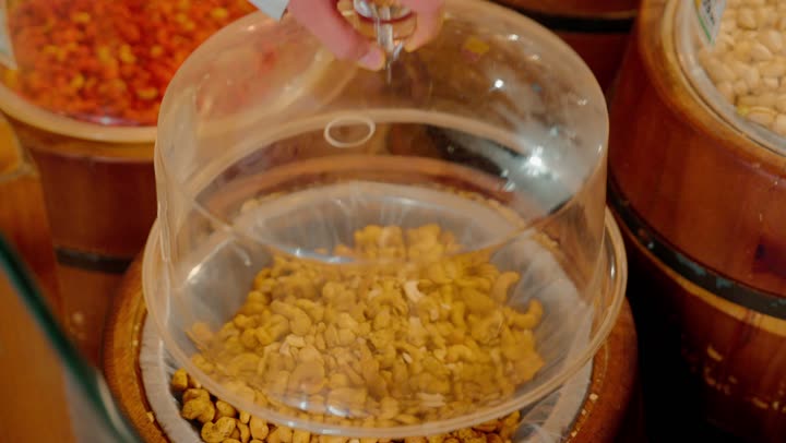 تصوير مقرب ليد رجل عربي خليجي اماراتي يقوم باختيار مكسرات الكاجو من عبوات البيع بالوزن داخل السوبر ماركت، التسوق الذكي واختيار المواد الغذائية الجافة بعناية، مفهوم شراء المكسرات الطازجة، جودة المنتجات الغذائية داخل المتاجر الحديثة