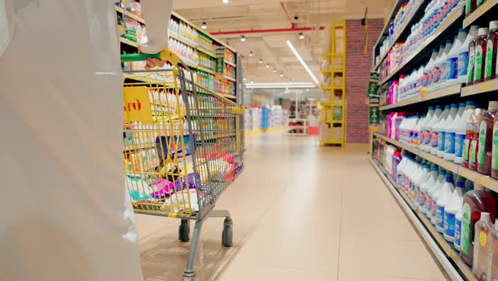 اقتناء المستلزمات واللوازم المنزلية، تصوير مقرب لرجل عربي خليجي اماراتي يرتدي الزي التقليدي يجر عربة التسوق داخل السوبرماركت، الاستفادة من العروض والخصومات على المنتجات