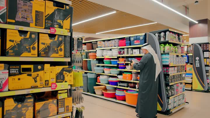 رجلان عربيان خليجيان اماراتيان يرتديان الكندورة و الغترة يقفان أمام أرفف المنتجات داخل المتجر يقومان بالمصافحة، ايماءات السعادة و السرور، تسوق المستلزمات المنزلية