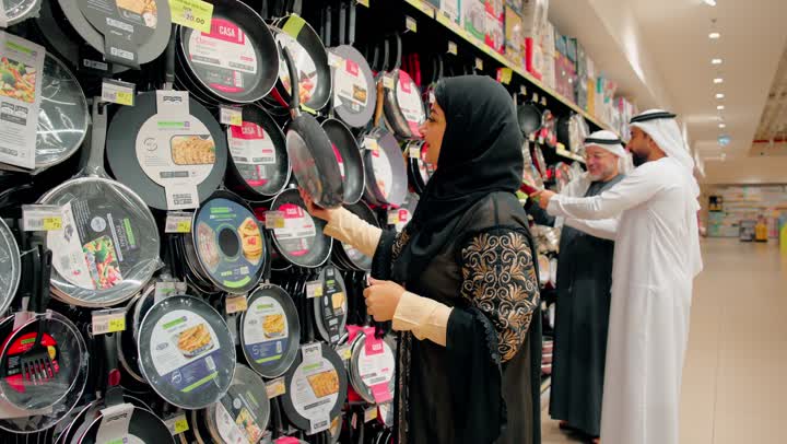 المشاركة في اختيار أدوات المطبخ، التعاون والترابط الأسري، عائلة عربية خليجية اماراتية ترتدي الزي التقليدي تختار أواني الطبخ داخل متجر أدوات منزلية، مفهوم التسوق العائلي داخل مركز تجاري، الاهتمام بتجهيز المطبخ بأدوات عملية