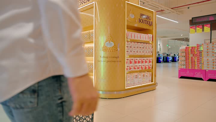 The concept of daily shopping, selecting luxury chocolate and confectionery products, an Arab Gulf Emirati man dressed in casual attire strolling inside a modern grocery store.