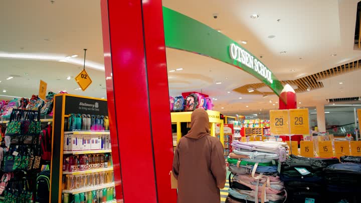 مفهوم التسوق للعودة إلى المدرسة، امراة عربية خليجية اماراتية تتسوق من قسم المستلزمات المدرسية ، عرض حقائب مدرسية ودفاتر وأدوات دراسة